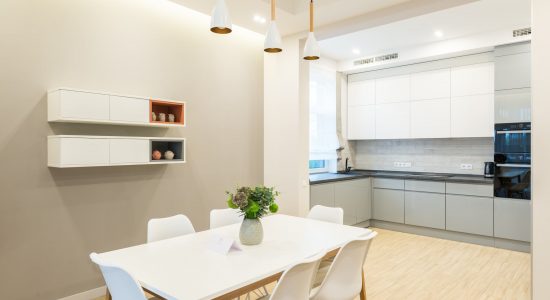 Interior kitchen corner with a dining table, long counter, and window in a white wall.